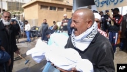 A Libyan man carries away partial remains of a man's body at Al-Jalaa hospital in Benghazi, February 21, 2011