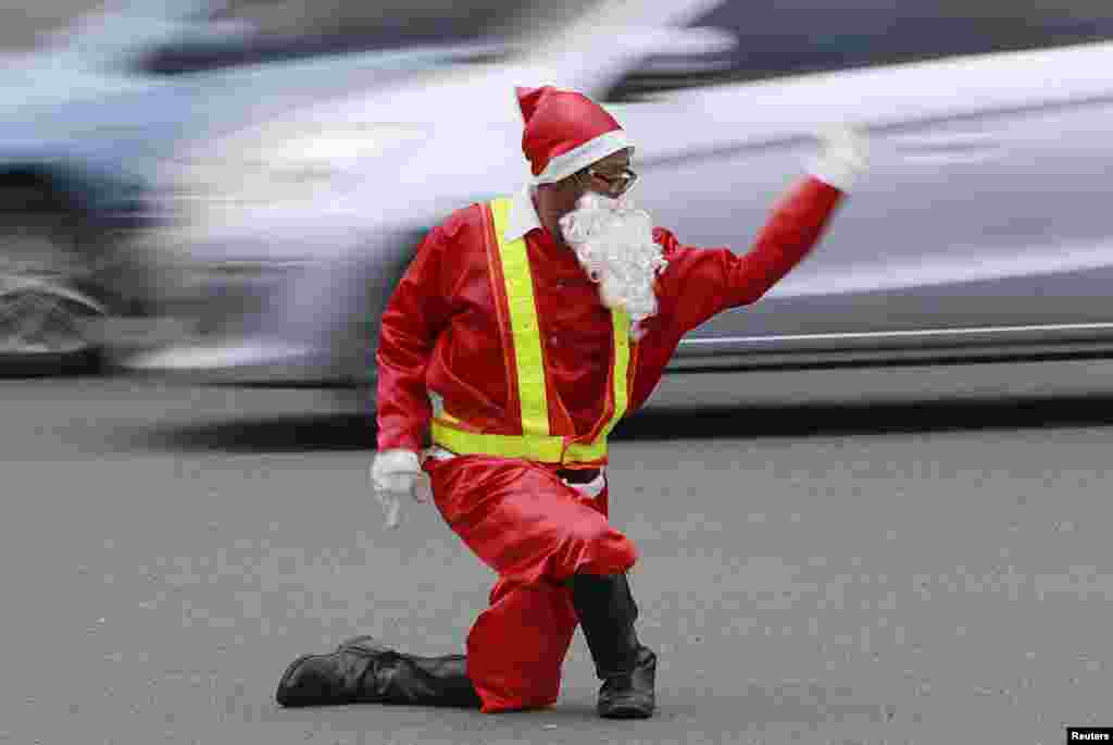 Traffic enforcer Ramiro Hinojas wearing a Santa Claus costume directs traffic flow at a busy intersection in Pasay city, metro Manila, the Philippines, Dec. 12, 2015.