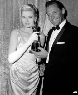 Best actress Grace Kelly receives her Oscar from the hands of presenter William Holden, on March 30, 1955, at the Pantages Theater in Hollywood, California.