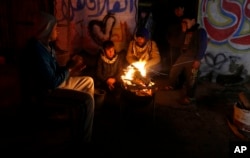 FILE - Palestinians, who get only several hours of electricity a day, sit around a fire outside their home in Gaza City, Jan. 25, 2016.
