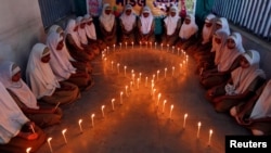 FILE - School girls light candles in the shape of a ribbon during a HIV/AIDS awareness campaign ahead of World Aids Day, in Ahmedabad, India, Nov. 30, 2016.