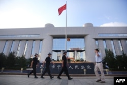 FILE - Police patrol at the gate of Kunming's Intermediate Court in Kunming, southwest China's Yunnan province.