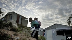 A boy carries a girl to school at a camp for earthquake displaced people in Port-au-Prince, Haiti, Dec 17, 2010