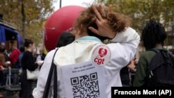A medical worker wearing a paper reading "No to QR code, No to Health Pass, the vaccine does not prevent for the virus transmission, Freedom to choose to be vaccinated" during a protest gathering outside the Health Ministry in Paris, Sept. 14, 2021. (AP Photo/Francois Mori)