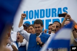 Honduran President Juan Orlando Hernandez raises his right fist as he mets with his party base, in Tegucigalpa, Honduras, Dec. 7, 2017.