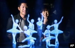 FILE - Tomoaki Ishizuka, left, and Yurika Yonekura watch the hologram of Japanese skater Yuzuru Hanyu, center, with ballet dancers at newly opened Hologram Dance Theater at Madame Tussauds in Tokyo, April 28, 2016. (AP Photo/Eugene Hoshiko)