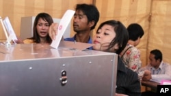 An unidentified Cambodian woman sticks out her head as she tries to cast her ballot at a polling station in Phnom Penh, file photo. 