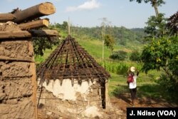 A woman carries a water barrel past a ruined home along Kenya's Mau forest. Kenyan authorities say settlers have for decades encroached on the protected forest.