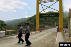 FILE - Police officers survey a bridge in Myanmar's Chin state, May 10, 2016, near the border with India where huge quantities of ingredients for the yaba drug are made.
