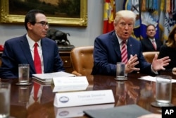 FILE - U.S. Treasury Secretary Steve Mnuchin listens as President Donald Trump speaks during a meeting on tax policy with business leaders in the Roosevelt Room of the White House, Tuesday, Oct. 31, 2017, in Washington.