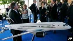 FILE - People gather around a model of C Series Bombardier airplane on the eve of the Farnborough aerospace show, Farnborough, England, July 13, 2008. Boeing has accused Bombardier of receiving government subsidies that let it engage in “predatory pricing.”