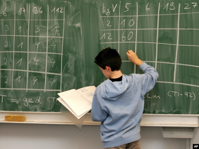 FILE: A student works on a math problem on the board, in preparation for the PISA test in 2004.