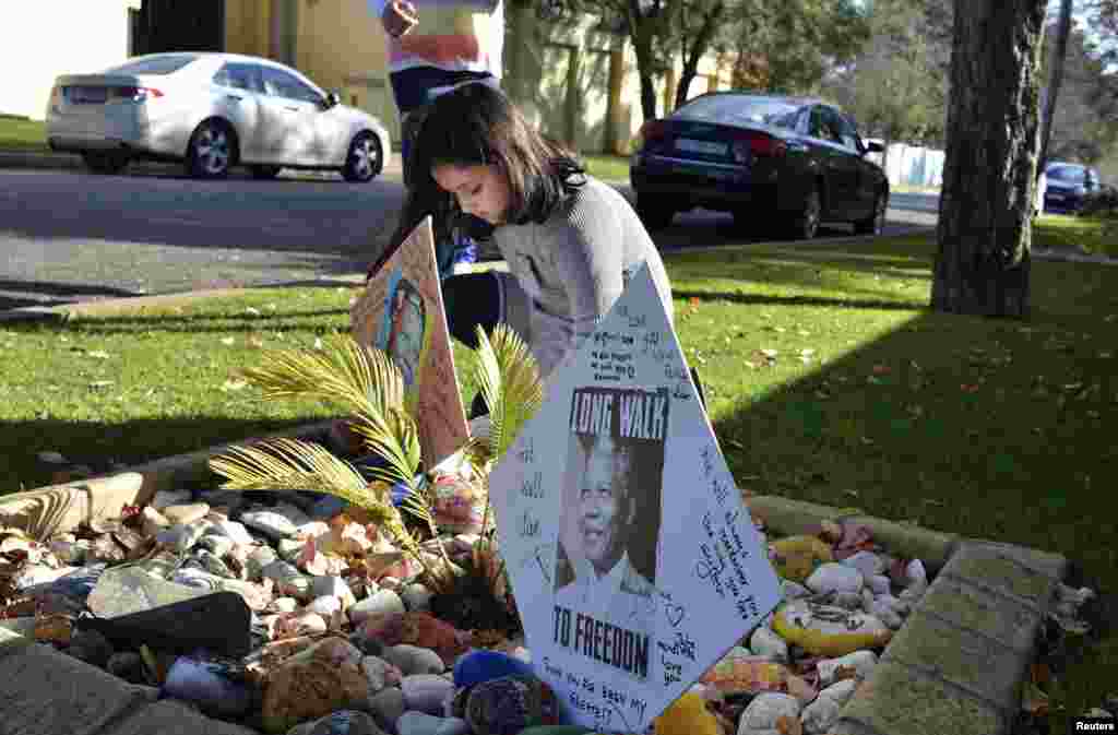 Seorang anak meletakkan pesan yang menyatakan dukungannya bagi kesembuhan mantan Presiden Afrika Selatan Nelson Mandela, di luar rumah kediamannya di Johannesburg, 9 Juni 2013. 