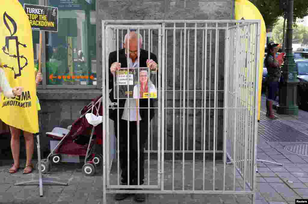 Amnesty International Belgium&#39;s Director Philippe Hensmans stands in a cage in front of the Turkish embassy in Brussels to protest against the detention of his Turkish counterpart Idil Eser.