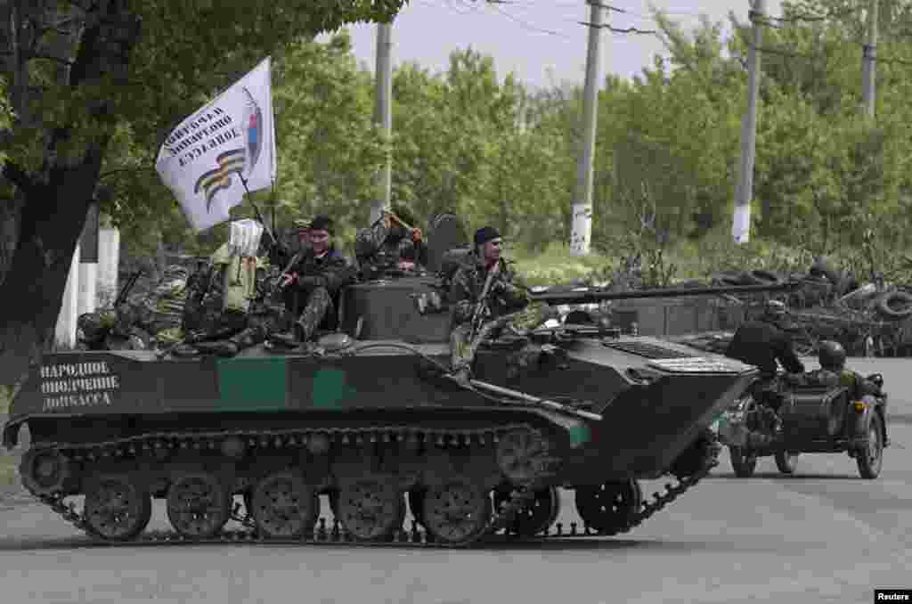 Pro-Russian armed men ride on top of an armored personnel carrier near Slovyansk, eastern Ukraine, May 5, 2014.