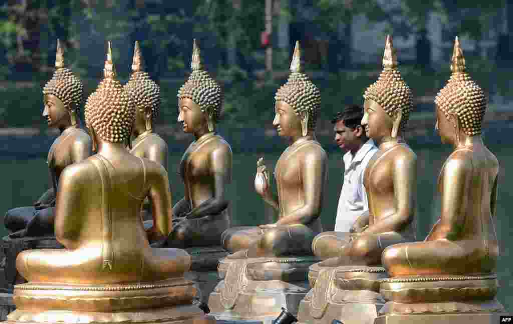 Seorang penganut Budha melewati Patung Buddha pada festival Poya, atau hari bulan purnama, di Candi Gangarama, Kolombo, Sri Lanka.