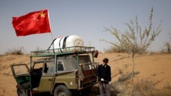 Wang Tianchang, 78, waters a tree planted on the border of the Gobi desert near Wuwei, Gansu province, China on April 15, 2021. The Wangs have been fighting desertification since they moved to the difficult land near the village of Hongshui in Wuwei in 1980. (REUTERS/Carlos Garcia Rawlins)