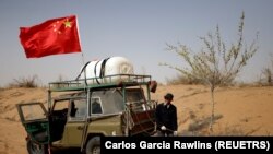 Wang Tianchang, 78, waters a tree planted on the border of the Gobi desert near Wuwei, Gansu province, China on April 15, 2021. The Wangs have been fighting desertification since they moved to the difficult land near the village of Hongshui in Wuwei in 1980. (REUTERS/Carlos Garcia Rawlins)