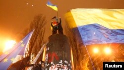 People fly Ukrainian and European Union flags following the toppling by protesters of a statue of Soviet state founder Vladimir Lenin in Kyiv, December 8, 2013.