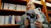 著名香港小说家、香港《明报》创办人查良镛在办公室里手持他的著作《书剑恩仇录》。（2002年7月29日）
