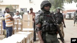 A police officer stands guard as electoral workers load ballot papers into trucks to be transported to polling stations, at the Independent National Electoral Commission in Yola, Nigeria, Feb. 15, 2019.