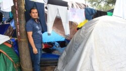 Josue Herman Sanchez Mendoza, 36, stands by the tent that he shares with his wife and a couple from Guatemala. (Dylan Baddour/VOA)