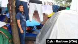 Josue Herman Sanchez Mendoza, 36, stands by the tent that he shares with his wife and a couple from Guatemala. (Dylan Baddour/VOA)