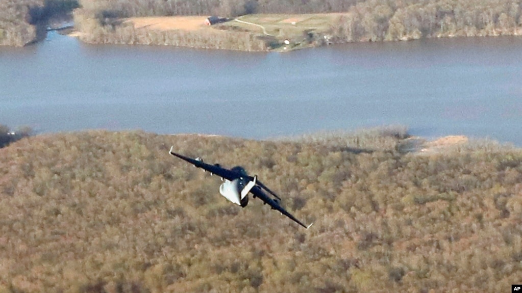 A military transport plane is seen below and on the starboard side from Air Force One while in flight from Palm Beach International Airport, Florida, to Andrews Air Force Base, Maryland, April 9, 2017.