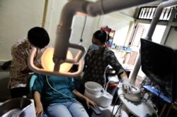 Seorang dokter gigi dan asisten yang merawat anggota keluarga mantan penebang kayu di sebuah klinik kesehatan nirlaba di Sukadana, Kalimantan Barat. (Foto: AFP/Bay Ismoyo)