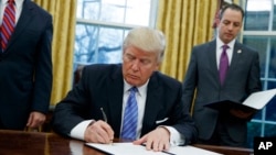 Presiden AS Donald Trump menandatangani perintah eksekutif untuk menarik AS dari pakta perdagangan Kemitraan Trans-Pasifik (TPP), di Gedung Putih (23/1). (AP/Evan Vucci)