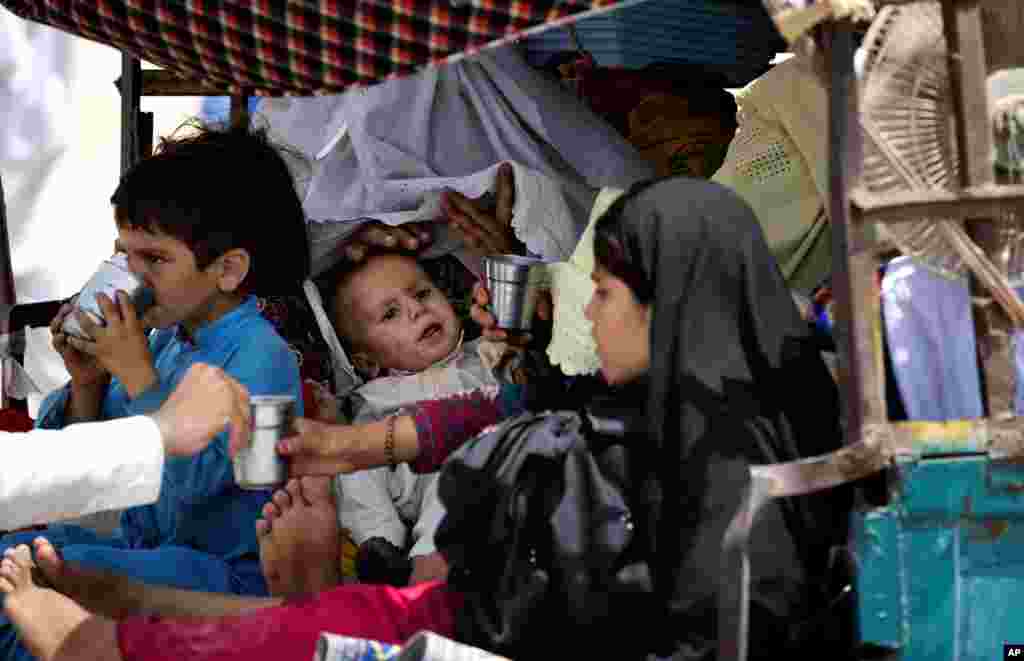 Thousands of villagers flee as the Pakistani army relaxes a curfew in troubled North Waziristan. Here local villagers offer water to fleeing tribal families after they arrive in Bannu, Pakistan, June 18, 2014.