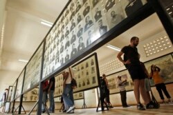 FILE - Tourists view portraits of victims executed by the Khmer Rouge regime at the Tuol Sleng Genocide Museum, formerly a notorious Khmer Rouge prison, in Phnom Penh, Cambodia, April 9, 2015.