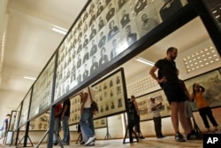 FILE - Tourists view portraits of victims executed by the Khmer Rouge regime at the Tuol Sleng Genocide Museum, formerly a notorious Khmer Rouge prison, in Phnom Penh, Cambodia, April 9, 2015.