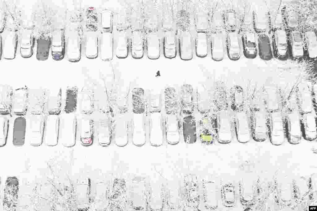 This overhead image shows a person walking across a parking lot in a residential area after snow fell in Beijing, China.