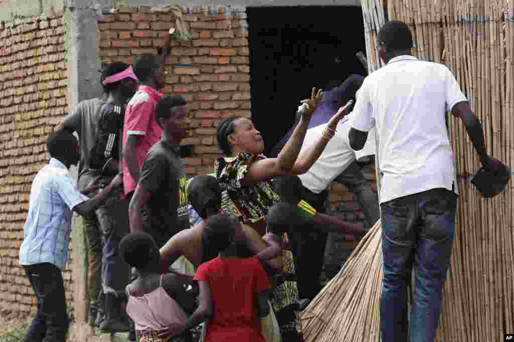 Une femme en pleure discute avec des manifestants qui pourchassent un membre présumé de la milice Imbonerakure de la jeunesse du parti au pouvoir à son domicile dans le quartier de Cibitoke de Bujumbura, au Burundi, jeudi 7 mai 2015.