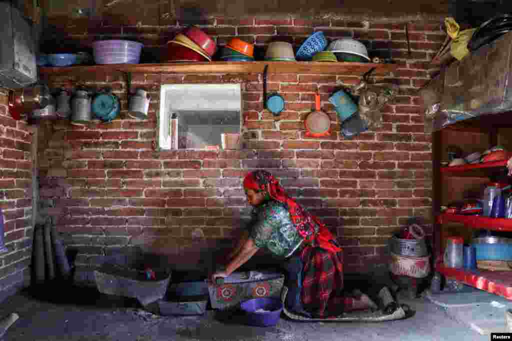 Maria Nieves, an indigenous Zapotec woman, grinds corn at her home in the rural village of San Bartolome Quialana, in Oaxaca state, Mexico, May 31, 2021.