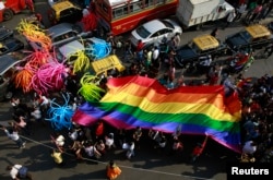 FILE - Participants holding a rainbow flag pass through a junction during a gay pride parade, which is promoting gay, lesbian, bisexual and transgender rights, in Mumbai, Jan. 31, 2015.
