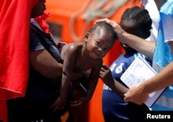 A member of Frontex touches a migrant child, intercepted aboard a dinghy off the coast in the Strait of Gibraltar, after arriving on a rescue boat at the port of Algeciras, southern Spain, July 21, 2018.