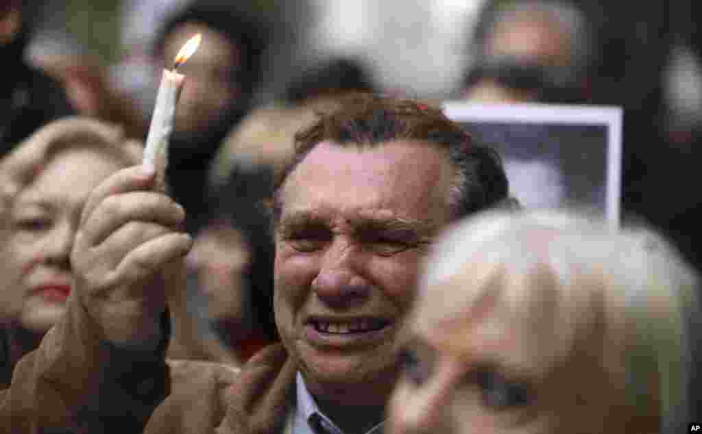 A man cries as he holds up a candle on the 25th anniversary of the bombing of the AMIA Jewish center that killed 85 people in Buenos Aires, Argentina.