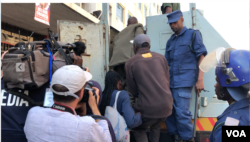 Zimbabwe police apprehend people they had found inside opposition Movement for Democratic Change Alliance offices in Harare following a raid there, Aug. 2, 2018. The people were arrested for leading protests that turned violent. (C. Mavhunga/VOA)