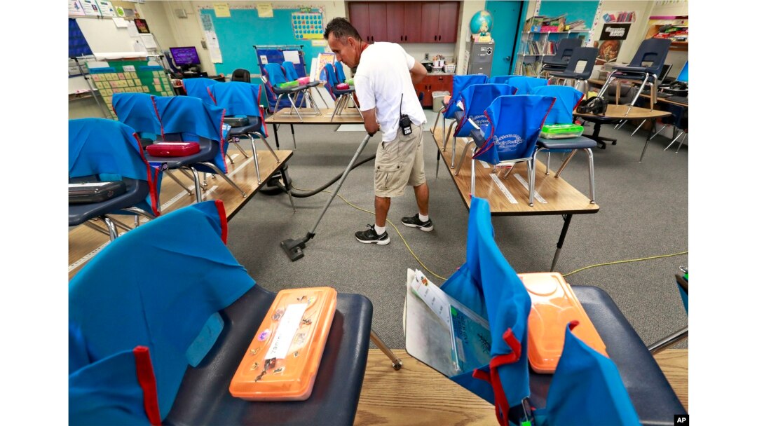 Custodian Jaime Cordona vacuums an empty second-grade classroom at San Marcos Elementary School in Chandler, Arizona, April 26, 2018.