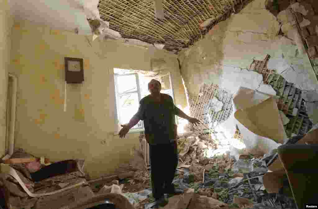 Anatoly Nosvo, 65, stands inside the living room of his home, which was damaged by shelling a day before in the village of Pisky, near Donetsk in eastern Ukraine.