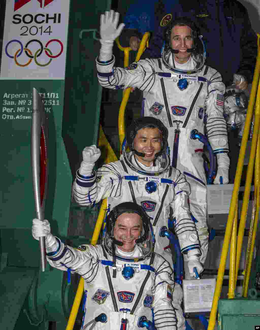 Japanese astronaut Koichi Wakata, center, Russian cosmonaut Mikhail Tyurin, bottom and U.S. astronaut Rick Mastracchio, pose with an Olympic torch prior the launch of Soyuz-FG rocket at the Russian leased Baikonur cosmodrome, Kazakhstan, Nov. 7, 2013.