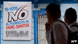 People walk by a placard that reads: "I vote NO the plebiscite FARC-Santos" in support of the "NO" in the upcoming referendum on the peace agreement in Cali, Colombia, Sept. 30, 2016.