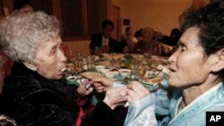 Warga Korea Selatan Lee Young-shil berusia 87 tahun (kiri) dan putrinya yang tinggal di Korea Utara Dong Myung-sook (66 tahun), saling menyuapi saat berlangsungnya makan malam bersama dalam reuni keluarga yang terpisah perang di tempat wisata "Diamond Mountain" Gunung Kumgang, Korea Utara (20/2).