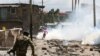 A riot policeman disperses residents during a clash over the demolition of homes at the Mukuru Kwa Njenga informal settlements to pave way for construction of the Nairobi Expressway with Industrial Area in Nairobi, Dec. 27, 2021.