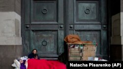 Maria Susana Silveira, 55, and Jorge Fernandez, 46, who live in the street as a team, rest outside Banco Nacion with their dog Toto, across the street from La Casa Rosada presidential house in Buenos Aires, Argentina.
