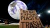 گلاسگو میں ہونے والی موسمیاتی کانفرنس میں ماحول کے تحفظ کے لئے سرگرم کارکن کے بیک پیک سے جھانکنے والا سائن جس پر پلاسٹک کا کچرا برآمد نہ کرنے کا مطالبہ درج ہے ۔ فوٹو اے ، نو نومبر دو ہزار اکیس 