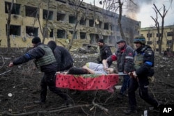 Ukrainian emergency employees and volunteers carry an injured pregnant woman from the damaged by shelling maternity hospital in Mariupol, March 9, 2022.