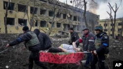 Ukrainian emergency employees and volunteers carry an injured pregnant woman from the damaged by shelling maternity hospital in Mariupol, Ukraine, March 9, 2022. 
